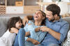 Familie lacht gemeinsam auf dem Sofa