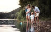 Familie steht an einem Fluss und schaut auf das Wasser.