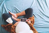 Schwangere Frau sitzt auf dem Bett und schaut auf ein Ultraschallbild.