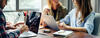 drei Personen sitzen mit Laptops zusammen am Tisch