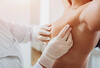 Brustkrebsvorsorge: Ärztin tastet Brust der Frau ab.