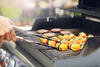 Gemüsespieße werden auf einem Gasgrill gewendet