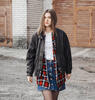 Junge Frau im Grunge-Stil mit rotem Karohemd, Lederjacke und Jeansrock