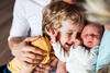 Neugeborenes Baby wird vom Bruder umarmt
