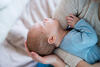 Mutter sitzt auf dem Bett und wiegt ihr neugeborenes Baby im Arm