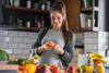 Schwangere bereitet gesundes Essen zu und schält eine Orange