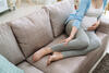 Schwangere liegt auf der Couch und hält ihre Hand aufs Bein