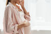 Hochschwangere lächelt und hält ihre Hand auf ihren Babybauch