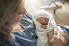 Mutter im Krankenhausbett kurz nach der Entbindung mit Neugeborenem im Arm