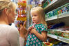 Mutter diskutiert mit kleiner Tochter vor Supermarktregal