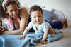 Mutter und Baby spielen liegend auf einer Decke