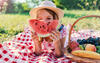 Mädchen isst eine Melone auf einer Picknickdecke