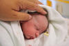 Hand streichelt neugeborenem Baby über den Kopf