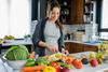 Schwangere bereitet Essen in der Küche zu, Gemüse und Obst