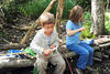 Zwei Kinder mit Schnitzmessern im Wald