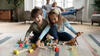 Junge und Mädchen spielen auf dem Wohnzimmerteppich mit Bauklötzen und Dinos