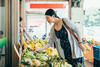 Schwanger mit Umhängetasche schaut sich Obst an einem Marktstand an