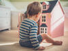 Kleiner Junge spielt mit Puppenhaus