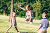 Drei Kinder spielen Gummitwist auf einer Wiese