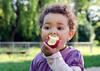 Kleinkind isst in der Natur einen Apfel mit der linken Hand