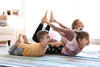 Mutter macht mit ihren beiden Kindern Yoga im Wohnzimmer