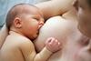 Mutter stillt mit freiem Oberkörper halb liegend ihr Baby