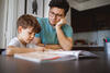 Grundschulkind macht Hausaufgaben mit Vater am Küchentisch