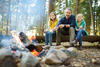 Familie sitzt am Lagerfeuer mit Stockbrot