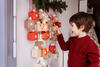 Kind steht aufgeregt vor seinem Adventskalender, der an der Wand hängt