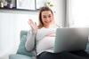 Schwangere Frau winkt in den Laptop