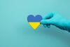 Hand, die ein Herz in ukrainischen Farben hält 