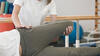 Physiotherapeutin führt bei einem Patienten eine Bein- und Hüftdehnungsbehandlung