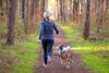 Frau beim Joggen im Wald mit ihrem Hund