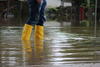 Mensch mit Gummistiefeln auf überschwemmter Straße