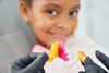 Kieferorthopäde zeigt Mädchen eine bunte Zahnspange