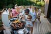 Vater mit kleinem Sohn grillt draußen während der Sommergartenparty der Familie.