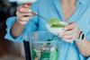 Nahaufnahme einer Frau, die während der Zubereitung eines Smoothies in der Küche Weizengrasgrünpulver hinzufügt