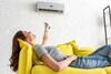 Junge Frau entspannt auf ihrem Sofa unter einer Klimaanlage
