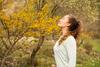 Junge Frau mit geschlossenen Augen atmet im Freien frische Luft im Sonnenlicht