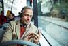 Älterer Mann sitzt im Bus und schaut auf sein Smartphone
